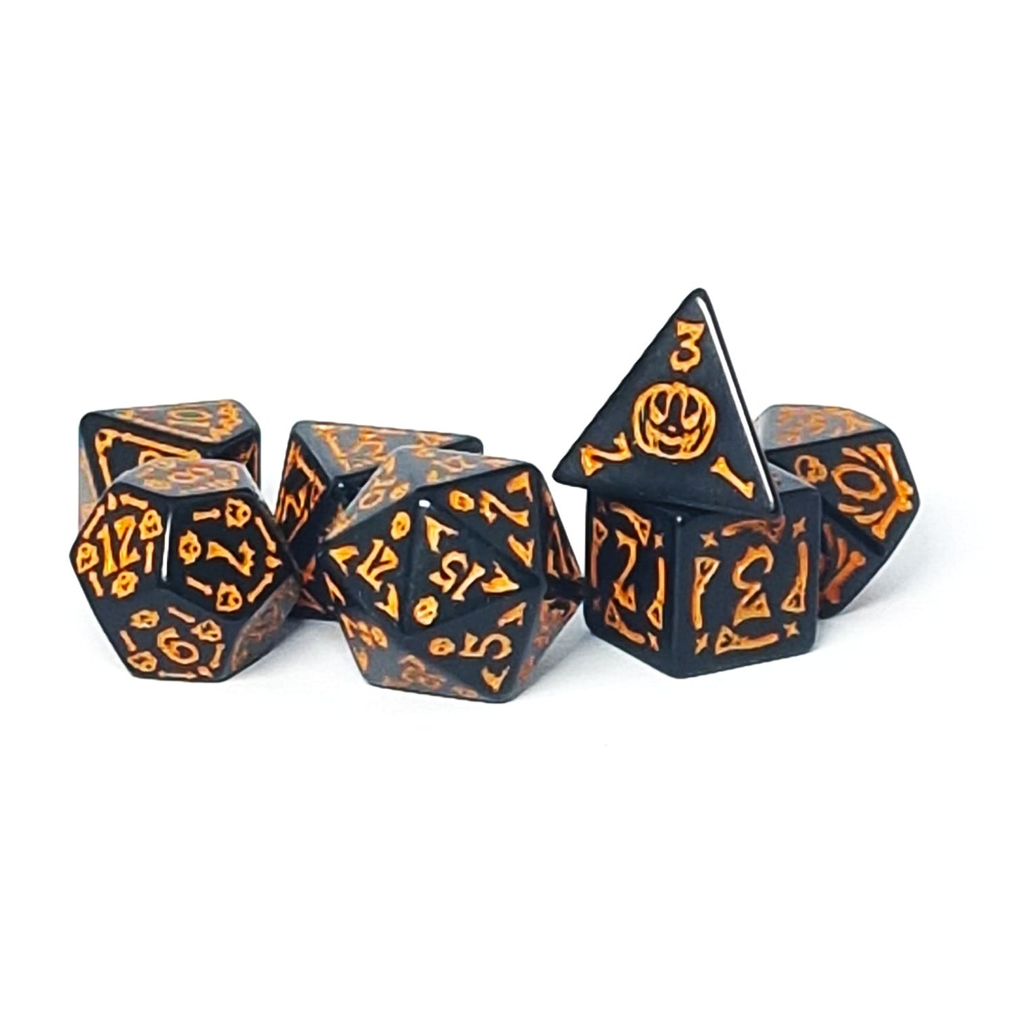 Set of black dice with orange Halloween-themed designs on a white background