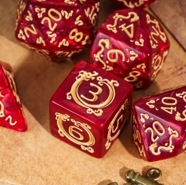 Red dice with gold numbering and symbols on a wooden surface