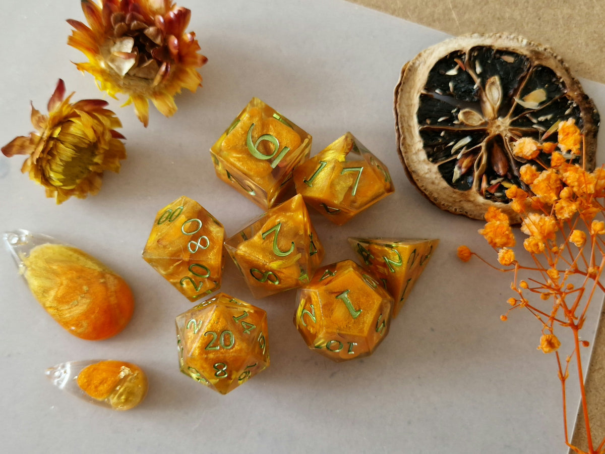 Pumpkin Patch epoxy resin dice set in shimmering orange and yellow with light green numbers.