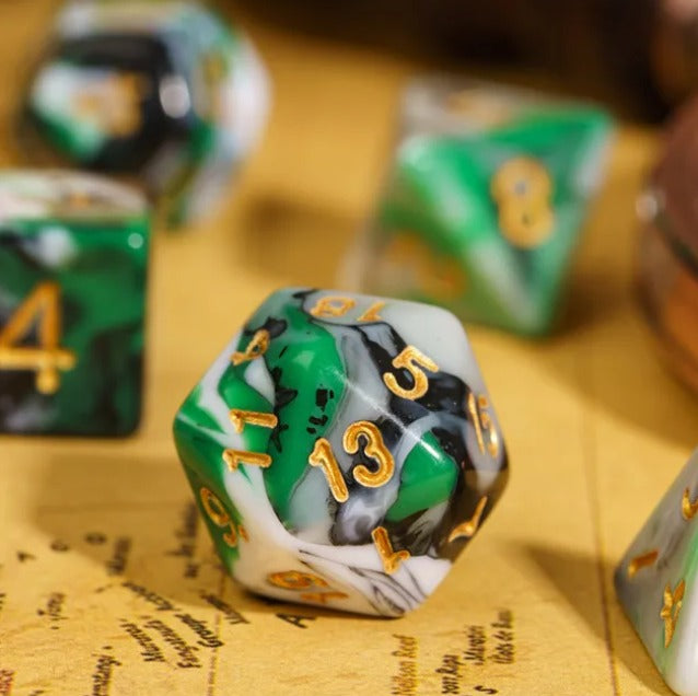 Close-up of a green and white polyhedral dice with gold numbers on a yellow surface.