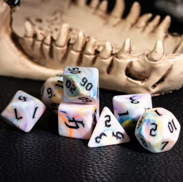 Set of dice with rainbow and black numbers on a dark surface with a skull in the background