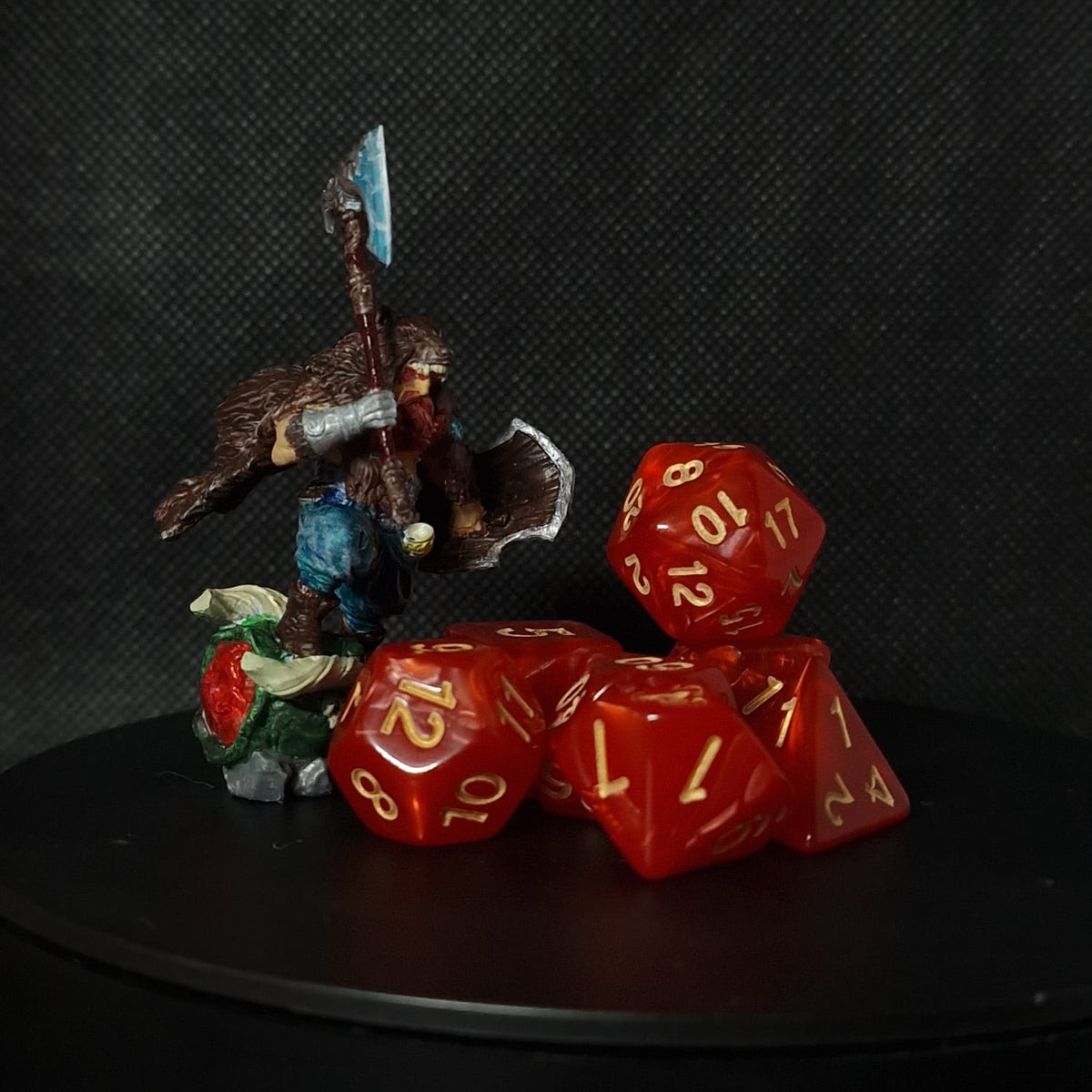 Red polyhedral dice for D&D with gold numbers on a black surface