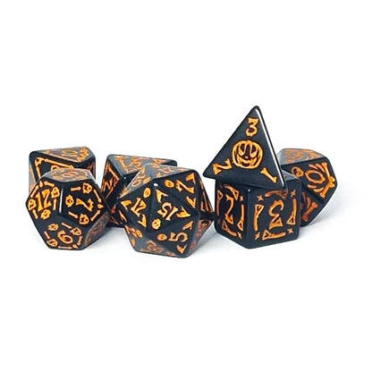 Set of black dice with orange Halloween-themed designs on a white background