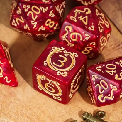 Red dice with gold numbering and symbols on a wooden surface