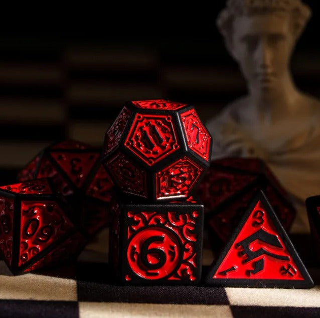 Red and black polyhedral dice set on a checkered surface with a blurred figure in the background.