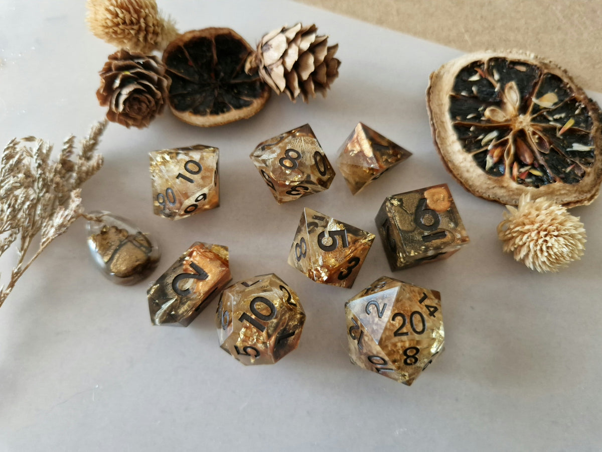 Golden Crown of Trees translucent epoxy resin dice with bronze and gold tones, leaf-like details and black numbers.